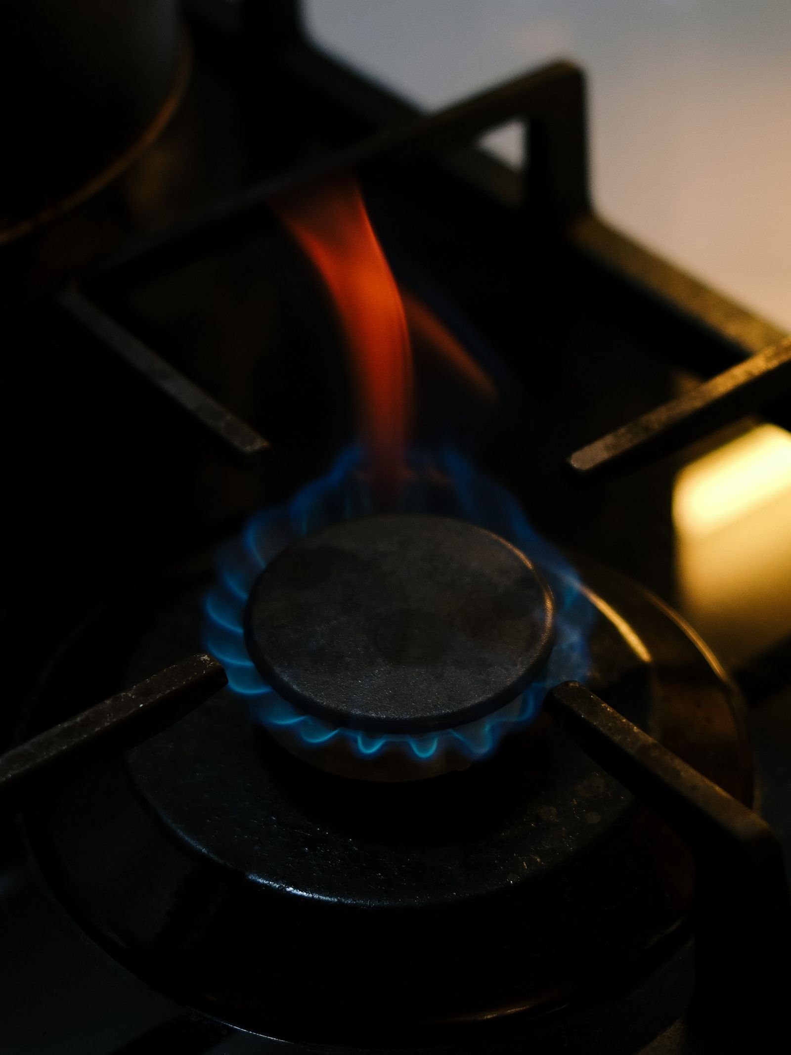 Lit gas burner with a blue flame in low light