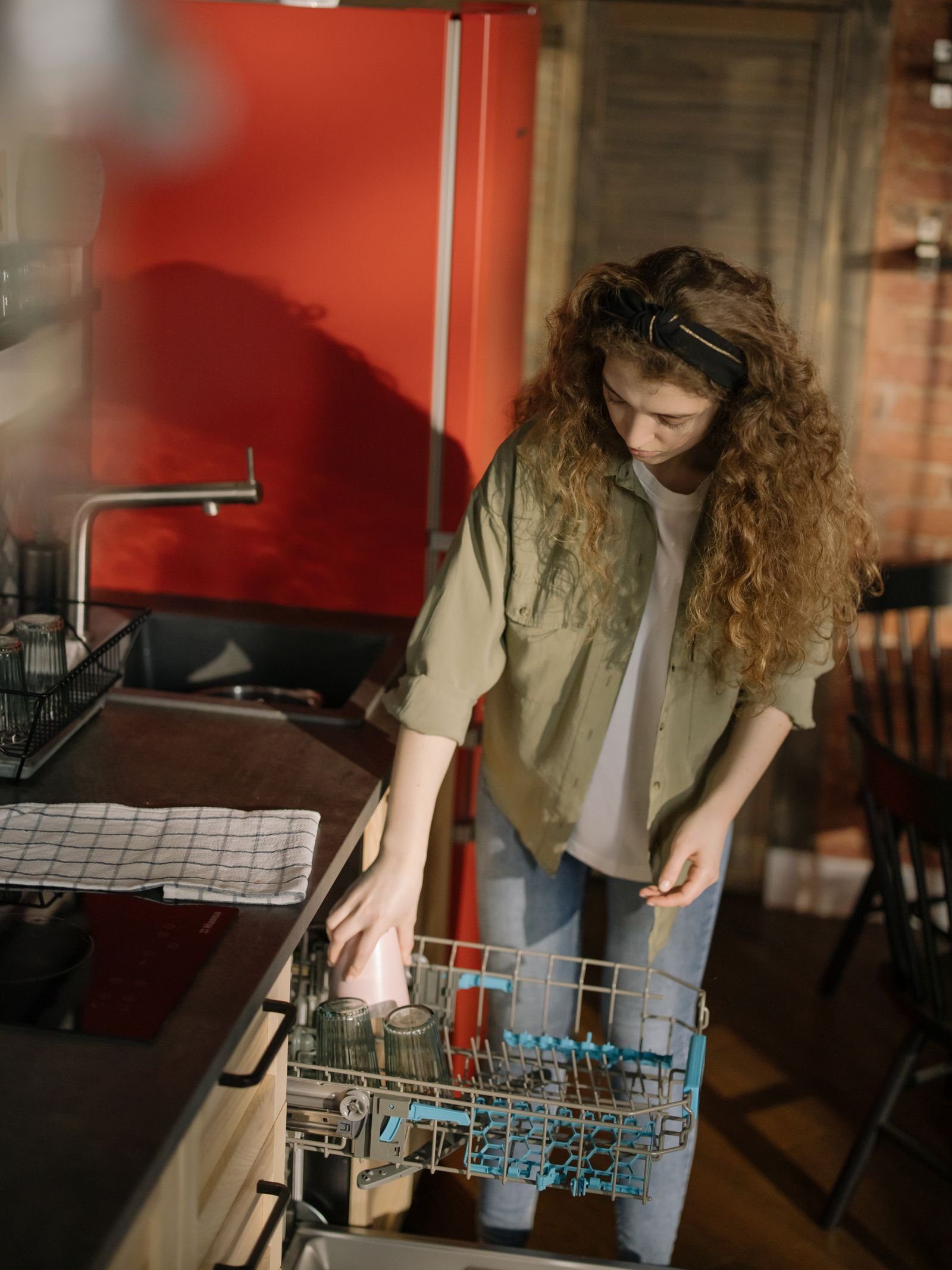 Woman loading plates into an open dishwasher