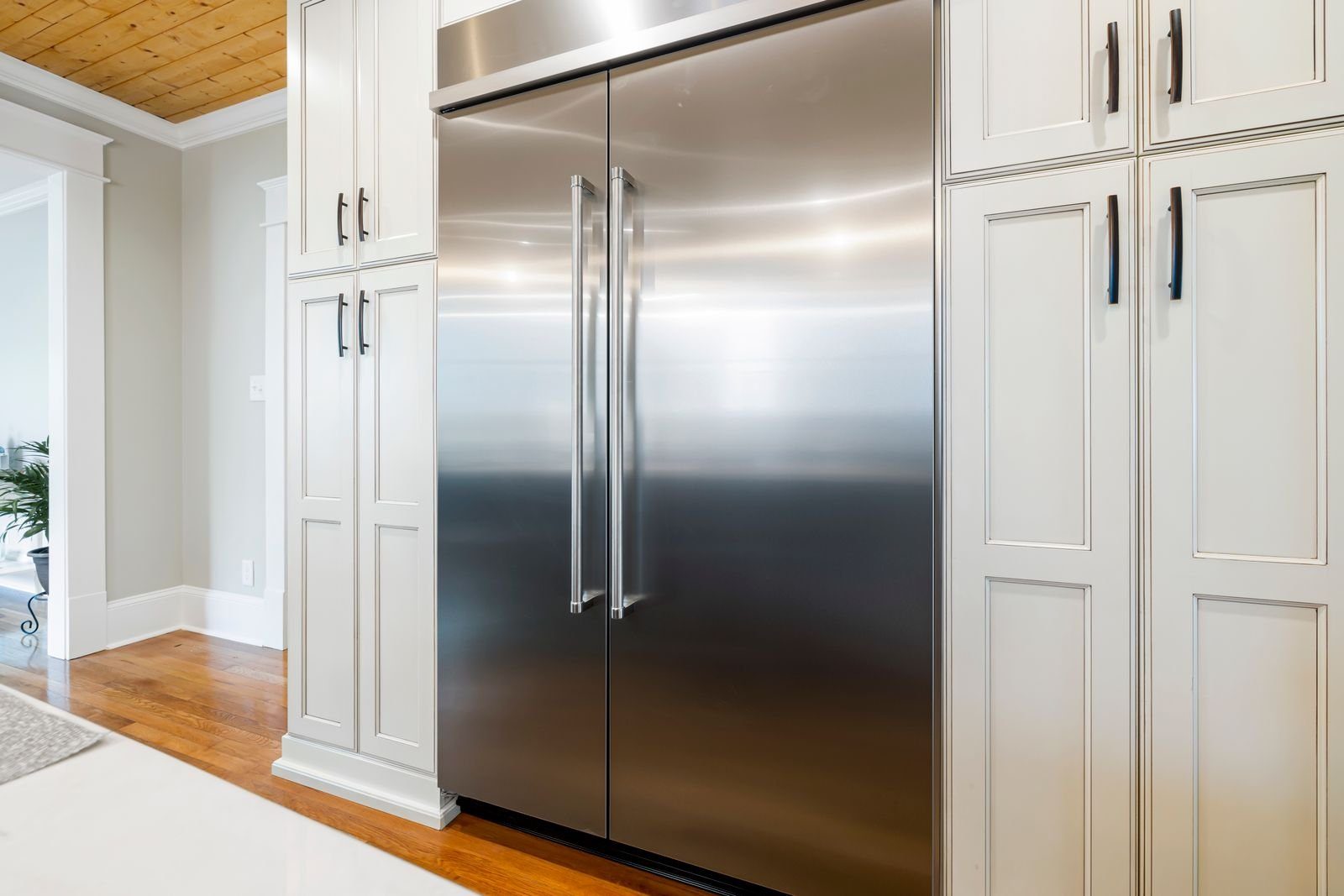 Stainless steel refrigerator built into white kitchen cabinetry