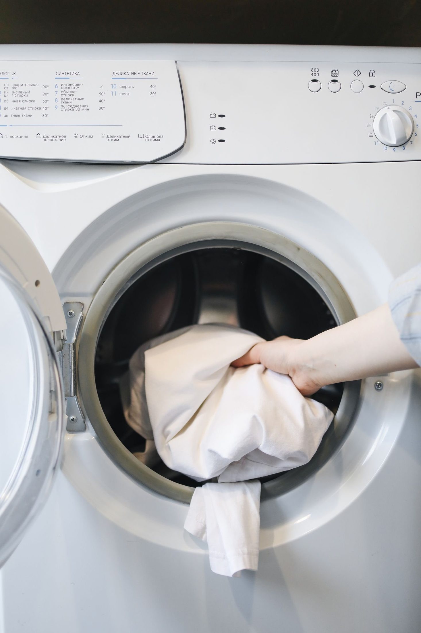 Hand loading laundry into a front load washing machine